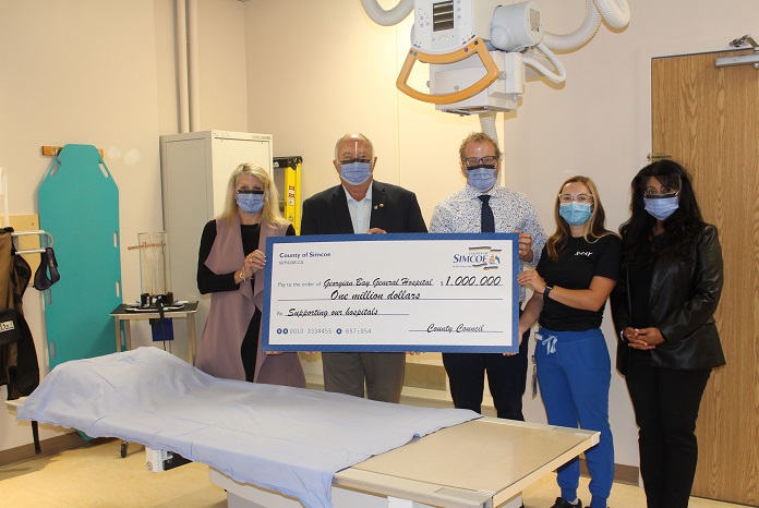 Five people holding an oversized cheque from the County of Simcoe for one million dollars.