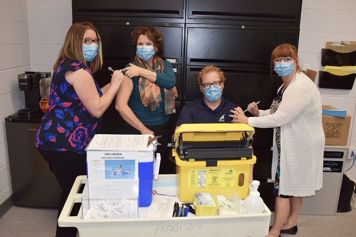 Three females and one male are shown getting flu shots