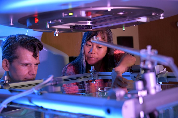 A woman and man look into a metal piece of machinery