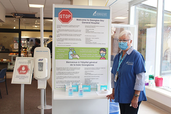 A volunteer poses in front of the sanitation station in the check in area.