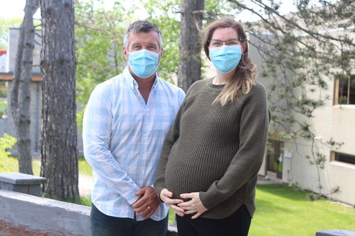 A pregnant woman and a man standing outside of the hospital